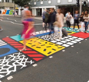 People walking across a colourful, painted footpath.