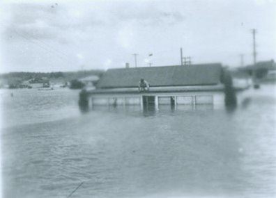 Man sitting on house in Maitland flood 1950